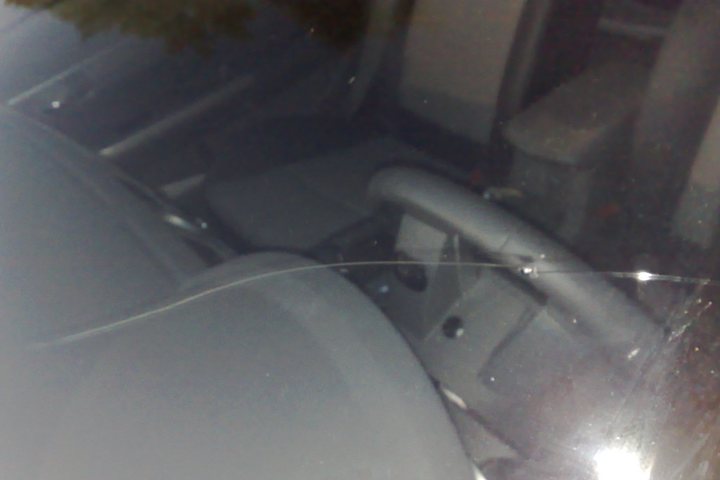 A long crack running across laminated windscreen glass, seen close up from inside the car